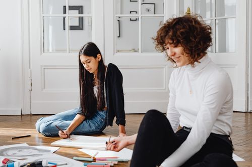 Free Two women engaged in a creative art session, sketching on the floor. Stock Photo