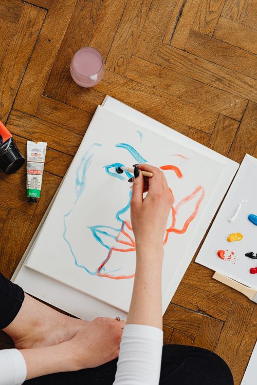 Free An artist paints a colorful abstract face on canvas, captured from above indoors. Stock Photo
