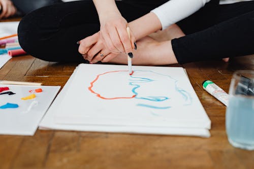 Close-Up Shot of a Person Painting while Sitting on the Floor