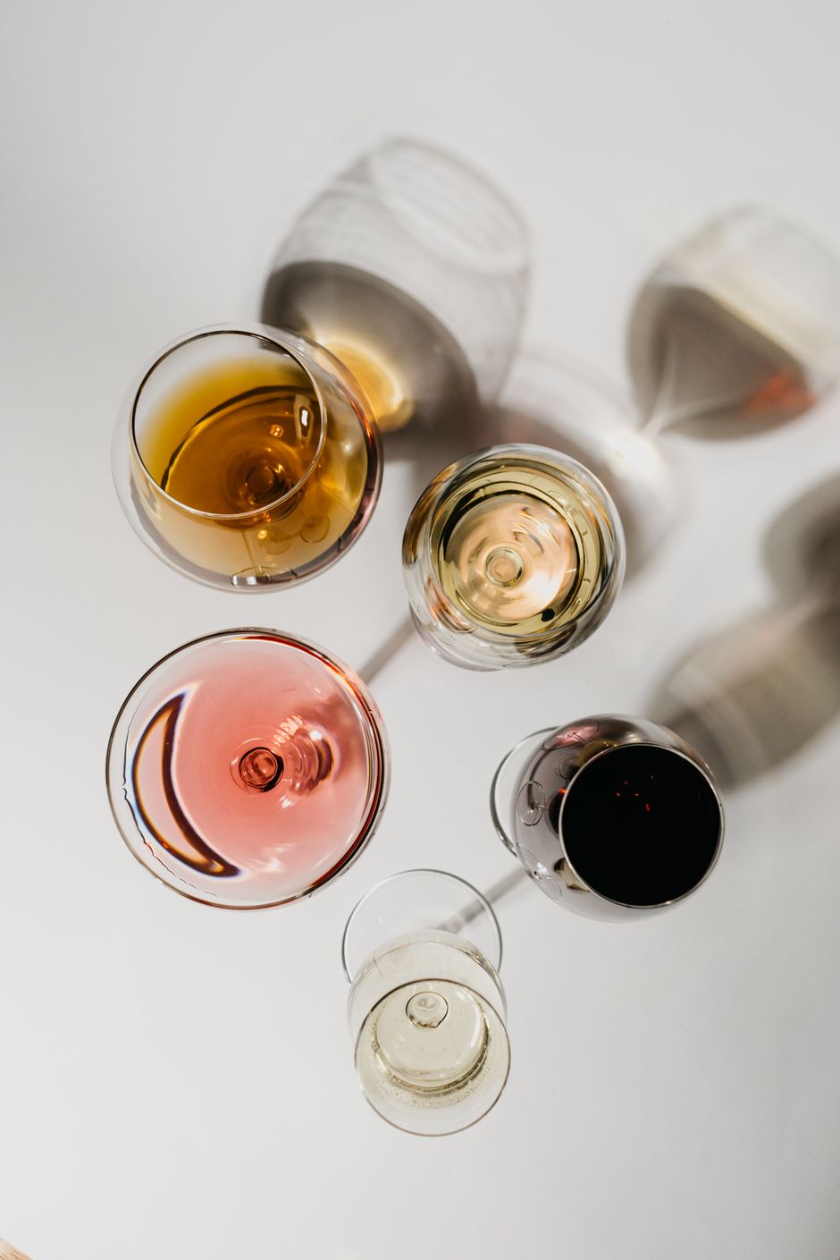 Top view of assorted wine glasses casting artistic shadows on a white surface.