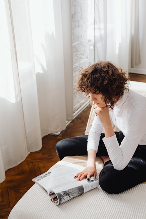 Woman in White Turtleneck Shirt Reading a Magazine