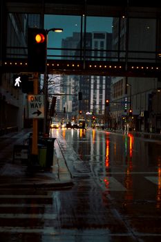 Rain-soaked street with urban traffic and reflections at night in downtown Minneapolis.
