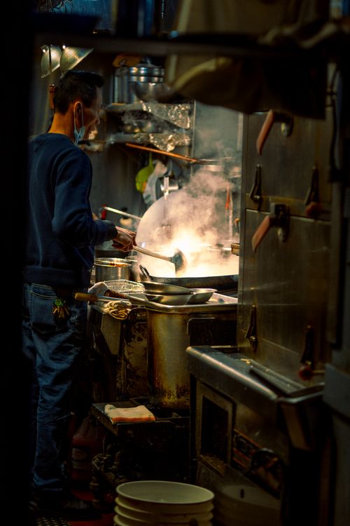 Free A chef cooks in an industrial kitchen with steam and warm lighting, creating an atmospheric scene. Stock Photo