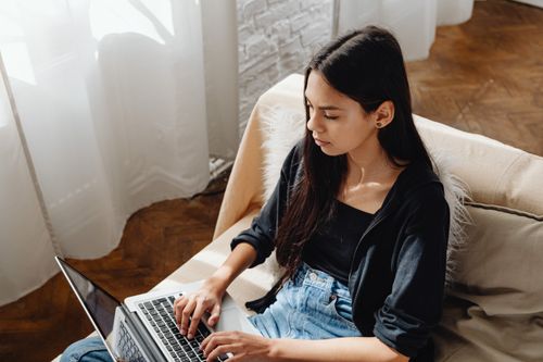 Free A woman focused on work while using a laptop at home, embodying the remote work lifestyle. Stock Photo
