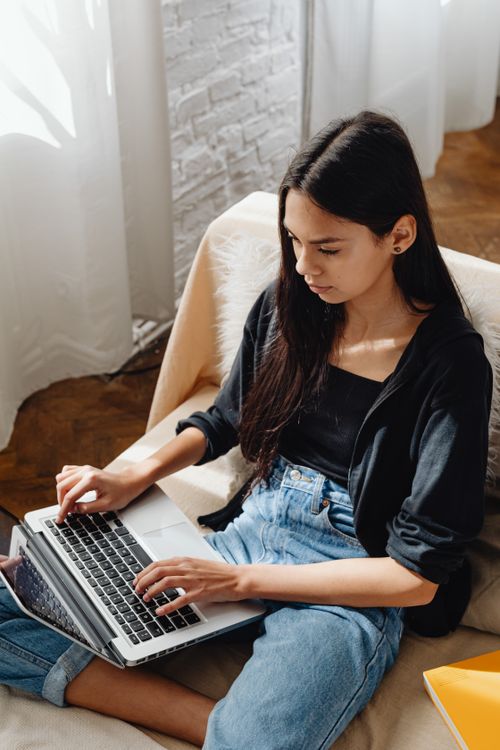 Photo of a Woman in Denim Jeans Typing on Her Laptop · Free Stock Photo