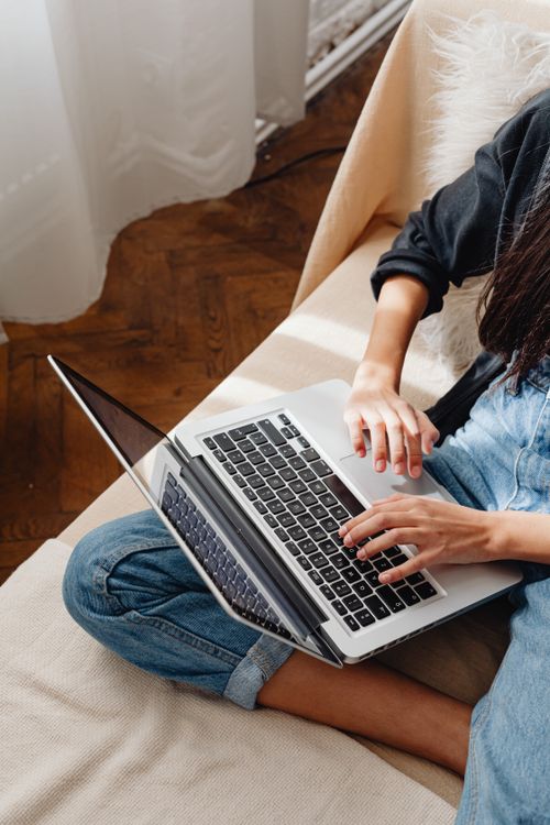 Free Young woman studying on a laptop at home, sitting on a couch, during the day. Stock Photo