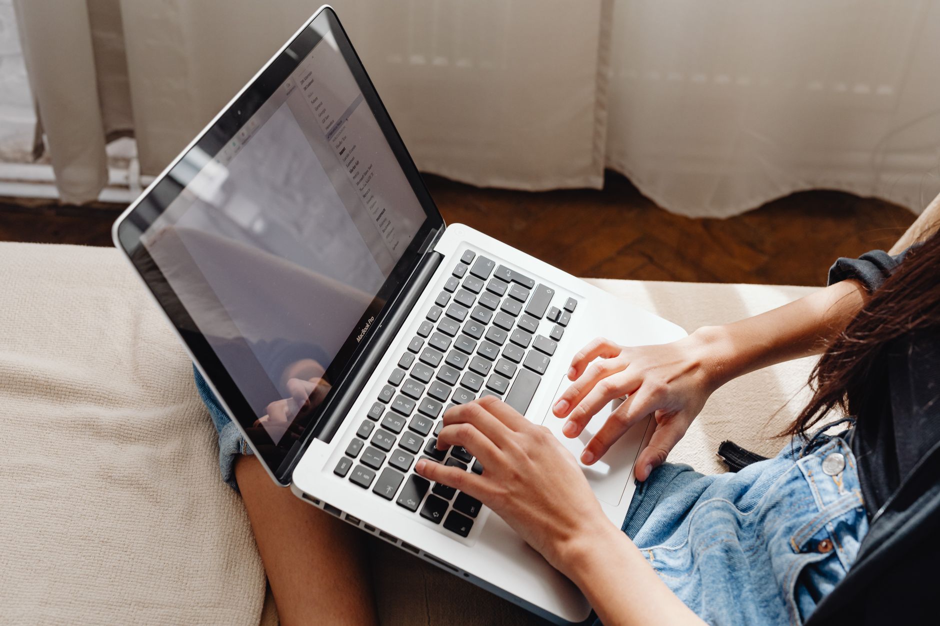 cara kerja robots.txt - Close-up of a woman's hands typing on a laptop while sitting comfortably indoors.