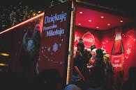 夜间活动时，一群人围聚在一辆喜庆闪亮的可口可乐拖车外