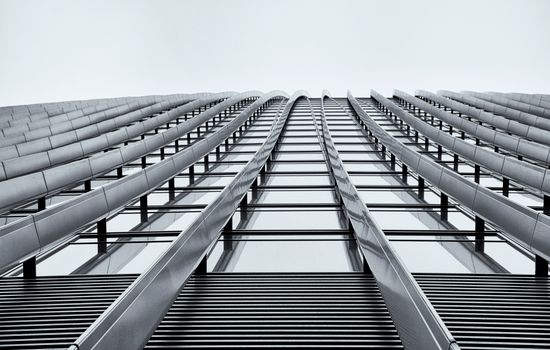 Low angle shot of a modern high-rise building showcasing its sleek architectural design in monochrome.