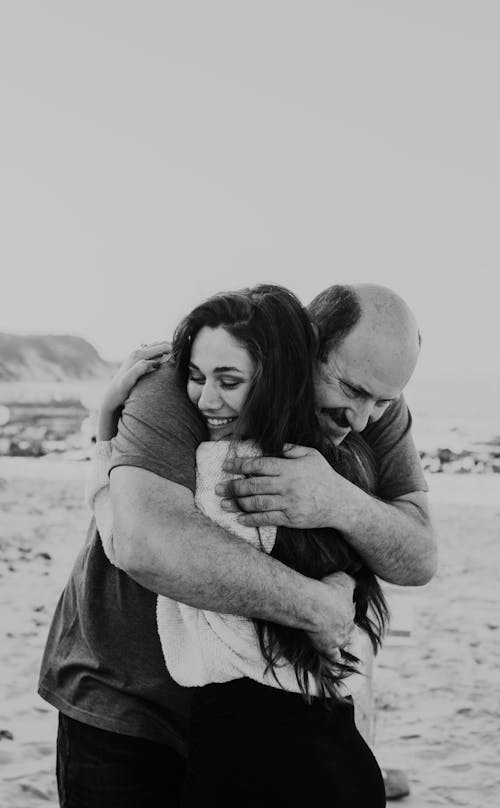 Cheerful senior father and daughter hugging on beach