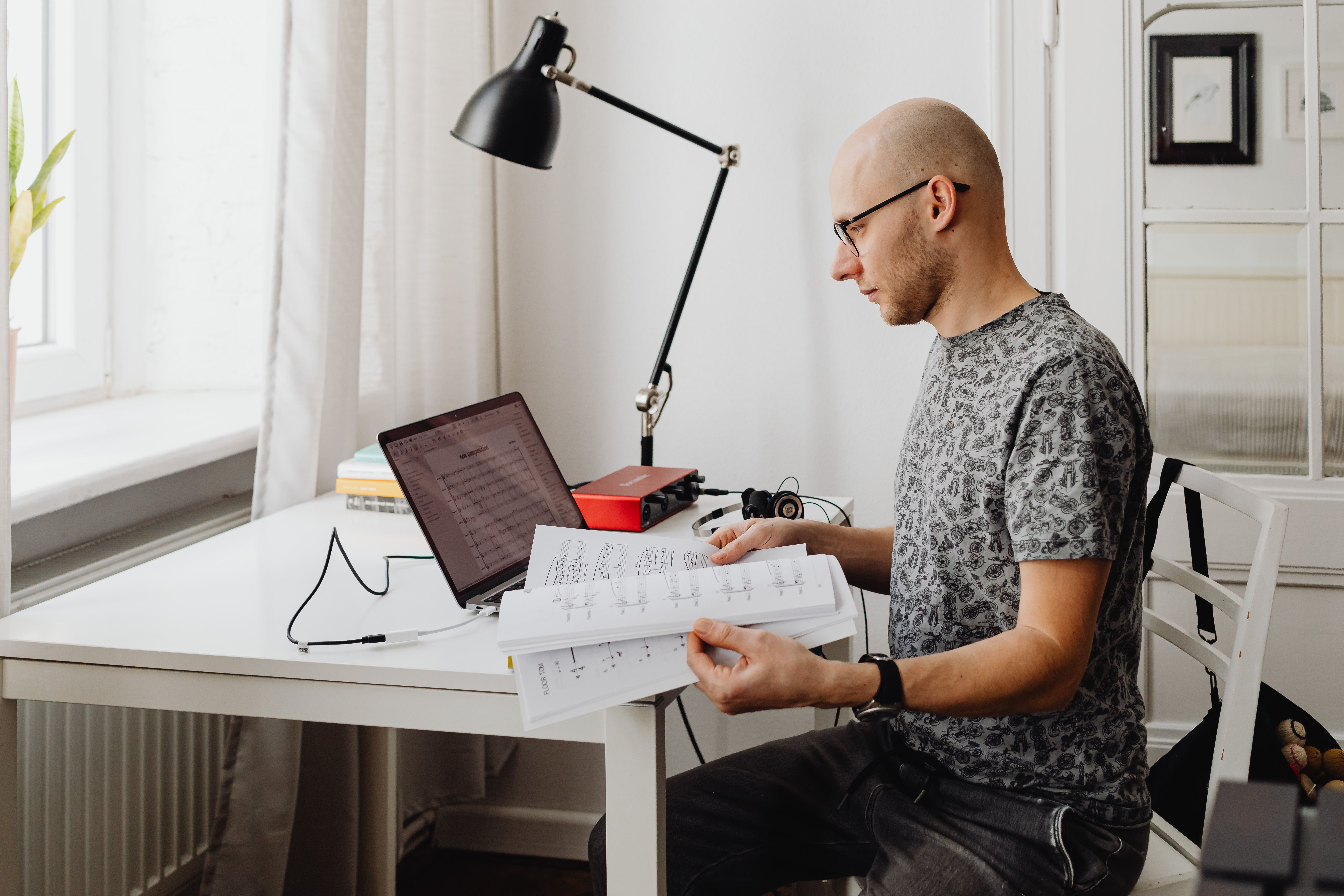 A young person sitting alone in a room, looking at a laptop with a thoughtful expression, surrounded by notes and a Bible