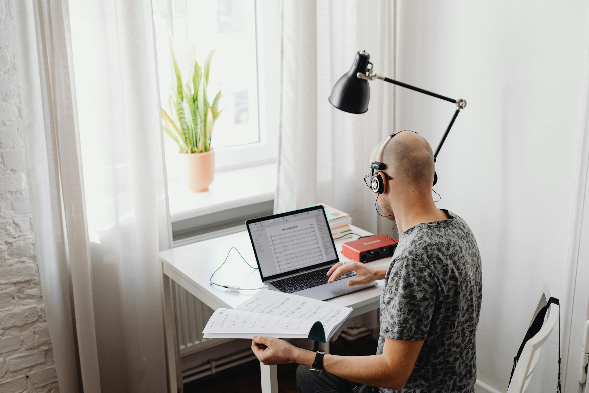 A Man in Printed Shirt Wearing Headset while Using His Laptop