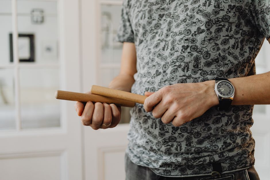 Detailed view of a person holding wooden claves, showcasing the instrument.