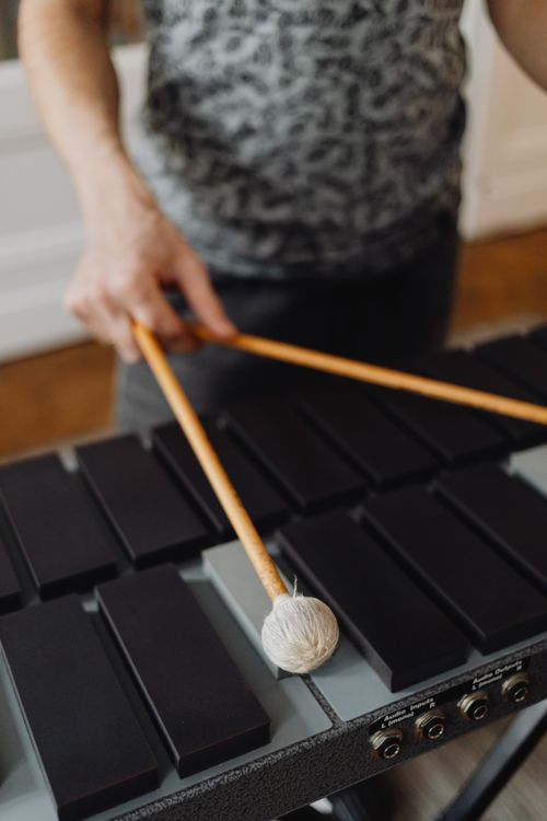 Free Close-up of a person playing xylophone with wooden mallets indoors. Stock Photo