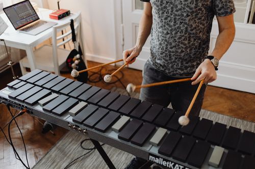Free A man using mallets to play an electronic percussion instrument inside a studio setting. Stock Photo