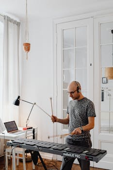 Adult musician plays electronic mallet instrument indoors, capturing a modern musical moment.
