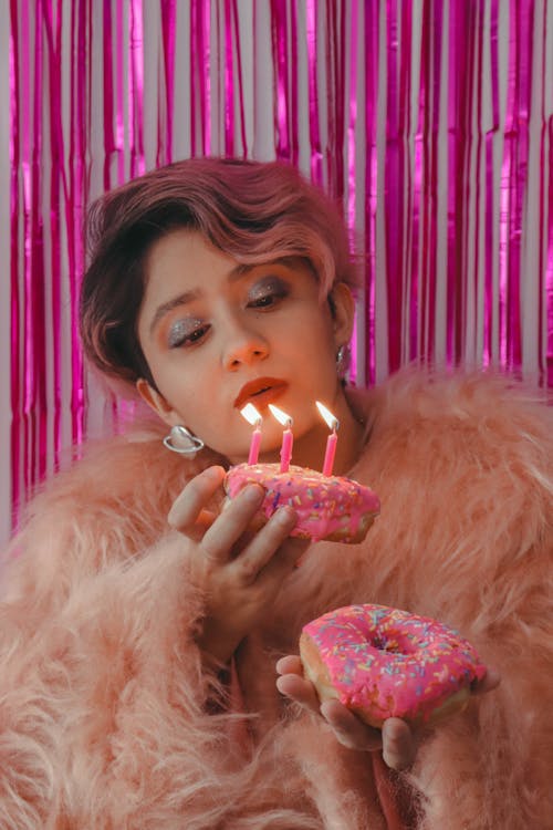 A Woman in Pink Fur Coat Holding Pink Doughnuts