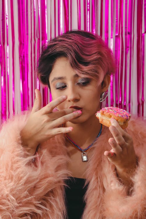 Free Chic Woman in Pink Fur Coat Holding a Doughnut  Stock Photo