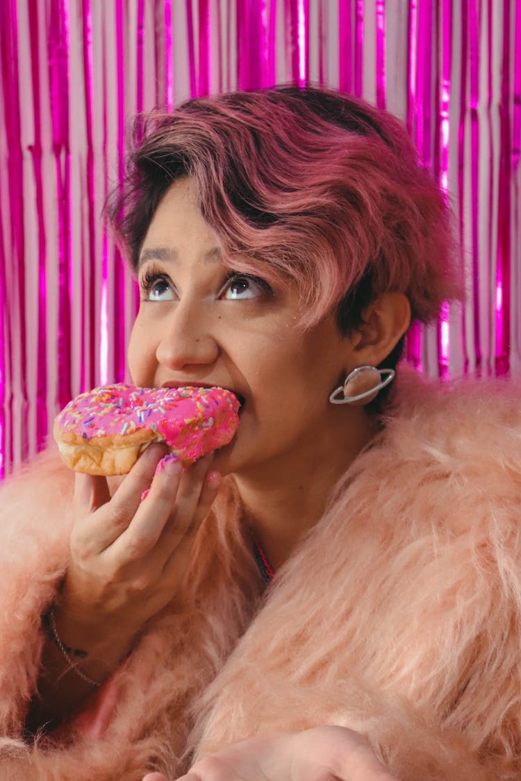 WomChic Woman In Pink Fur Coat Eating A Doughnut