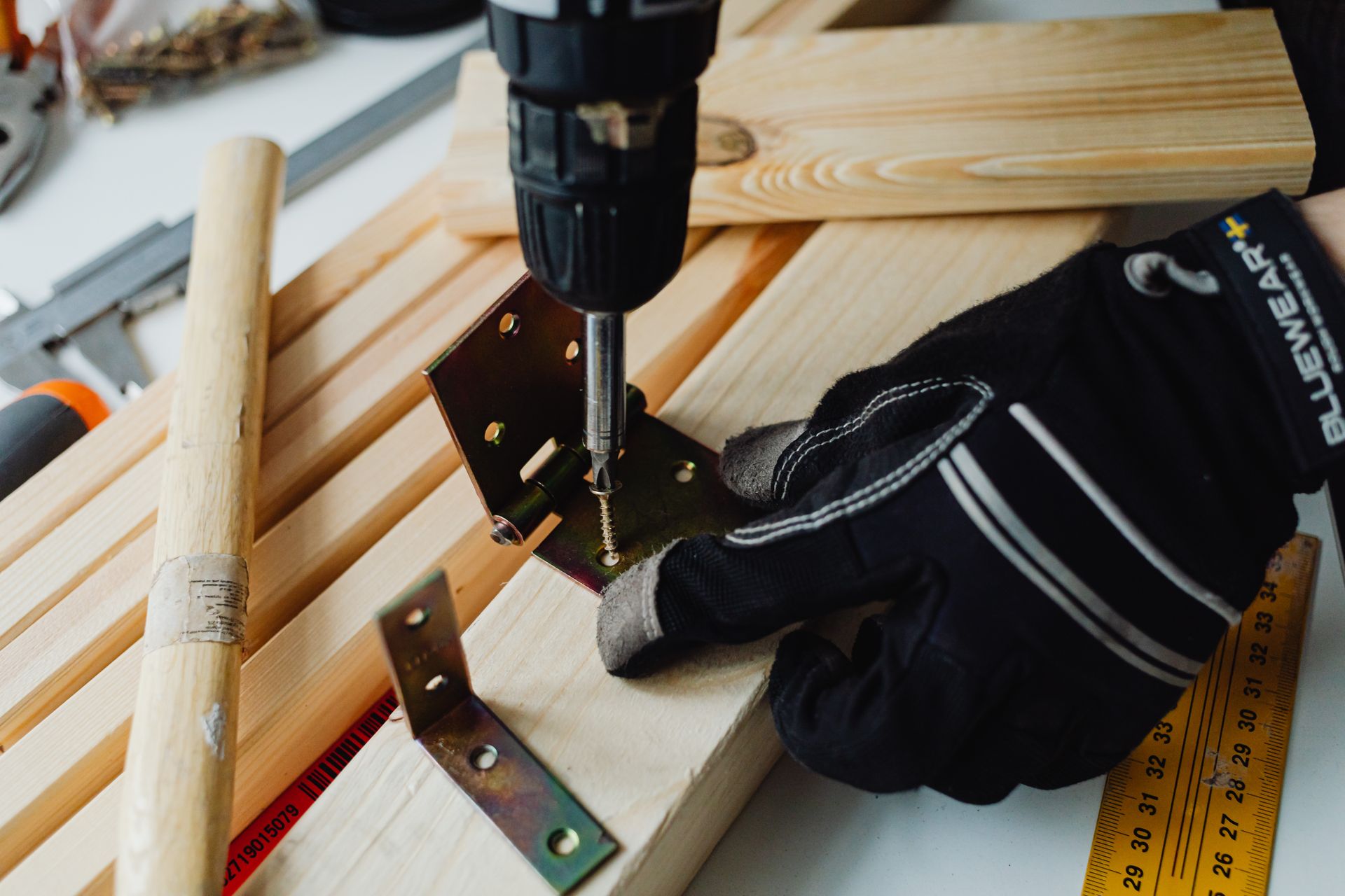 Carpentry work in progress with power drill and safety gloves