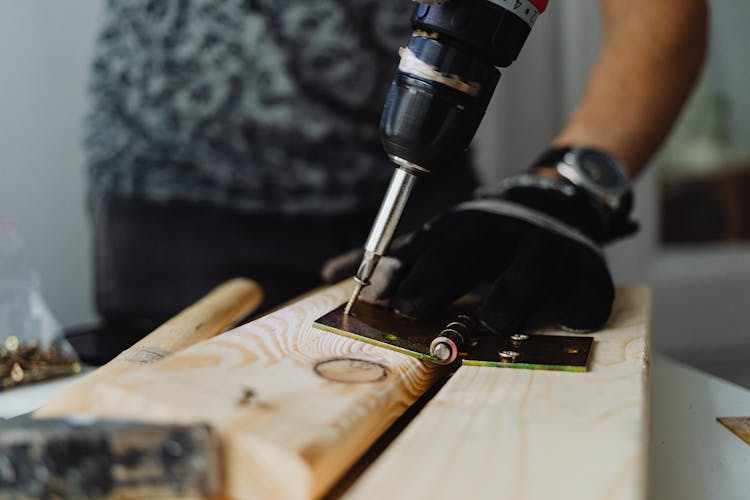 A Person Drilling A Screw