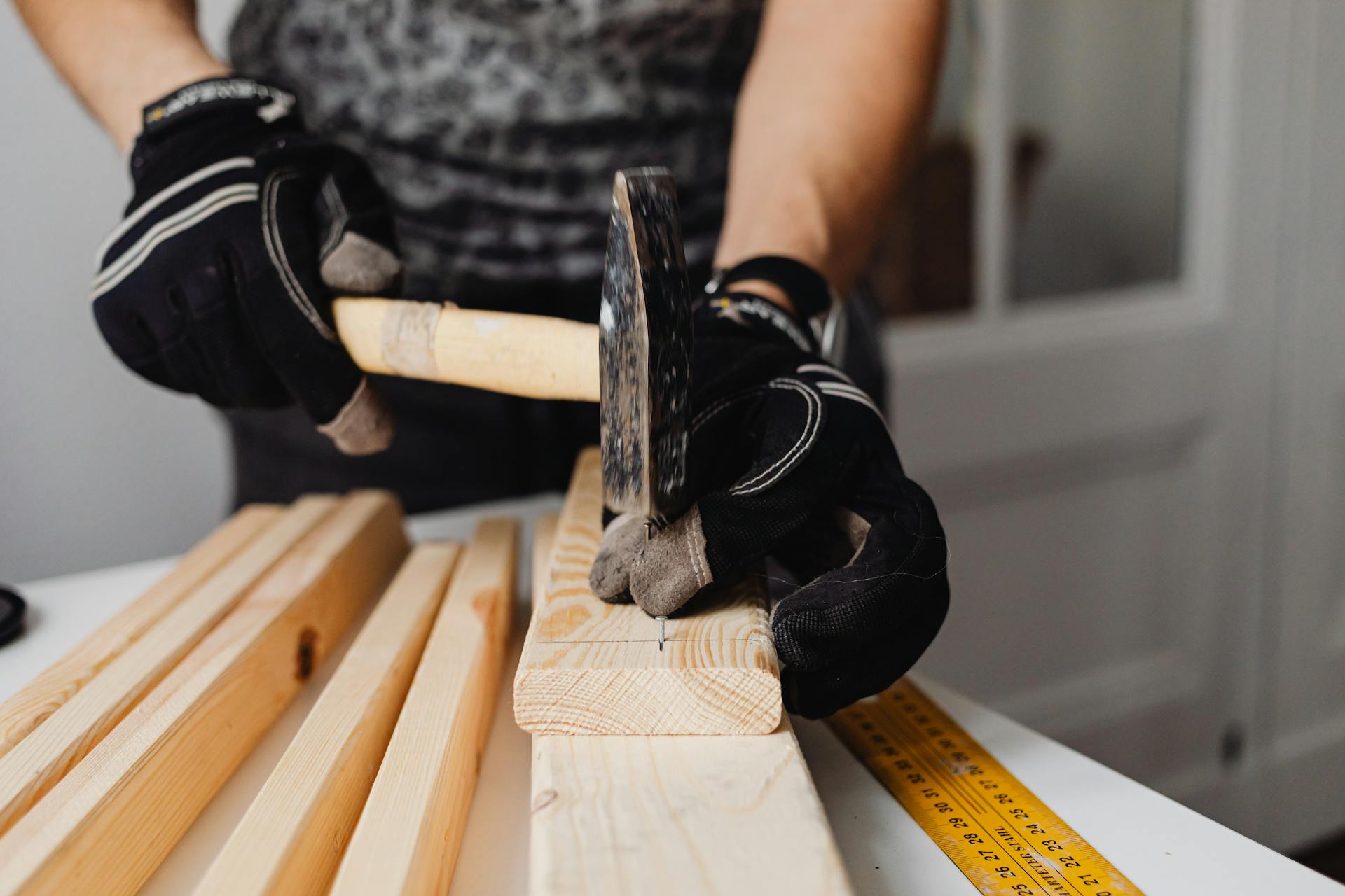 Craftsman hammering nails into wood, showcasing woodworking skills and tools in action.