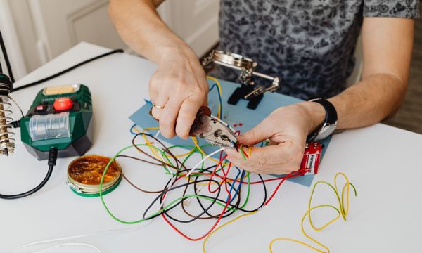 Electrician โ A technician precisely cuts and organizes colorful wires using pliers, showcasing expertise in wiring tasks.