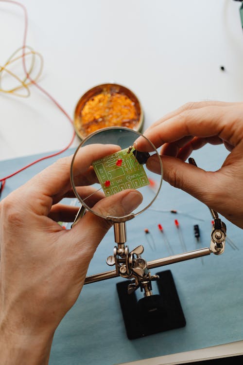 Person using Magnigying Glass for a Circuit Board 