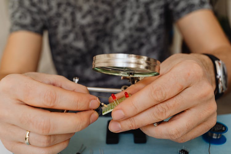 Close-up Of Man Fixing A Small Electronic Plate Under A Magnifier 