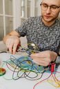 A Man with Eyeglasses Cutting Cables
