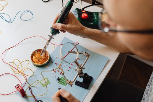 A technician skillfully soldering electronics with precision tools and wires on a workbench.
