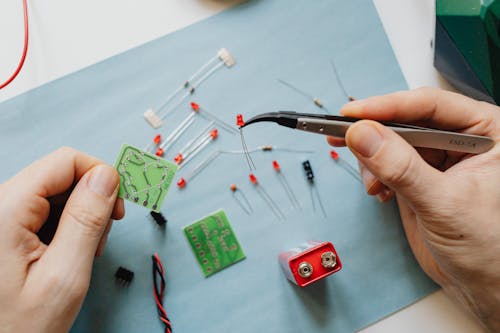 Person holding a Circuit Board and a Tweezer