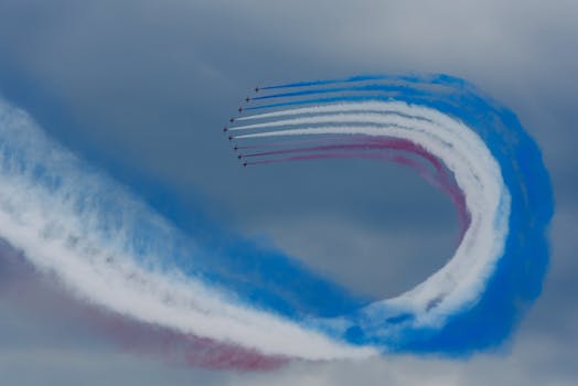 Aerobatic plane formation with tricolor smoke trails in the sky.