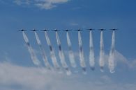 Air show with airplanes creating traces in blue sky