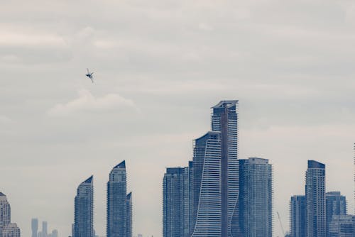 Military airplane flying above modern skyscrapers in city