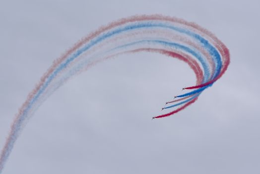 Low angle of aircrafts in row creating tricolor air tattoo in light sky on National Aviation Day