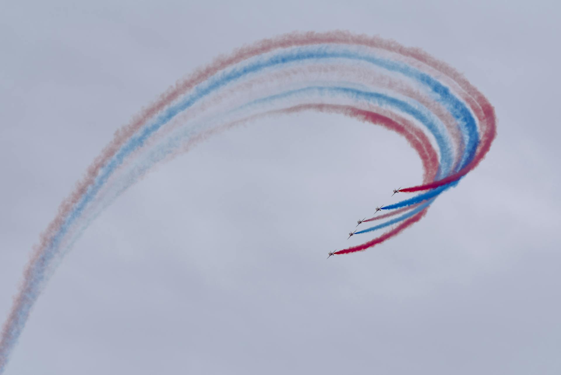 Low angle of aircrafts in row creating tricolor air tattoo in light sky on National Aviation Day