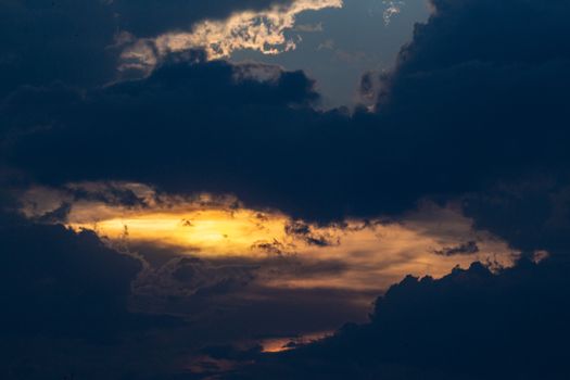 A breathtaking dark cloudscape with golden sunlight peeking through, captured at sunset.