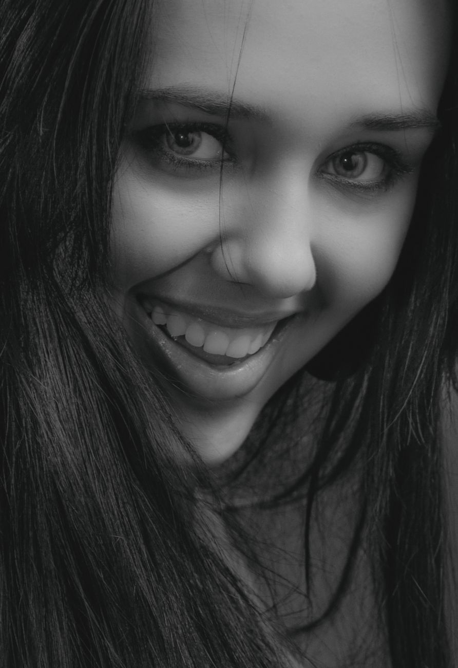 Close-up monochrome portrait of a smiling young woman, capturing a joyful expression.