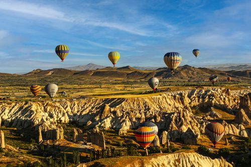 Free Hot air balloons soar over Cappadocia's unique rock formations on a sunny day. Stock Photo