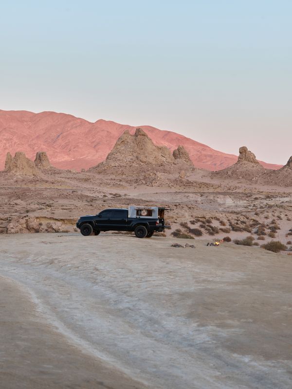 Black pickup with a camper shell parked in open desert