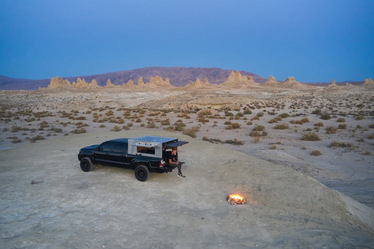 A Man Sitting At The Back Of A Camper Truck