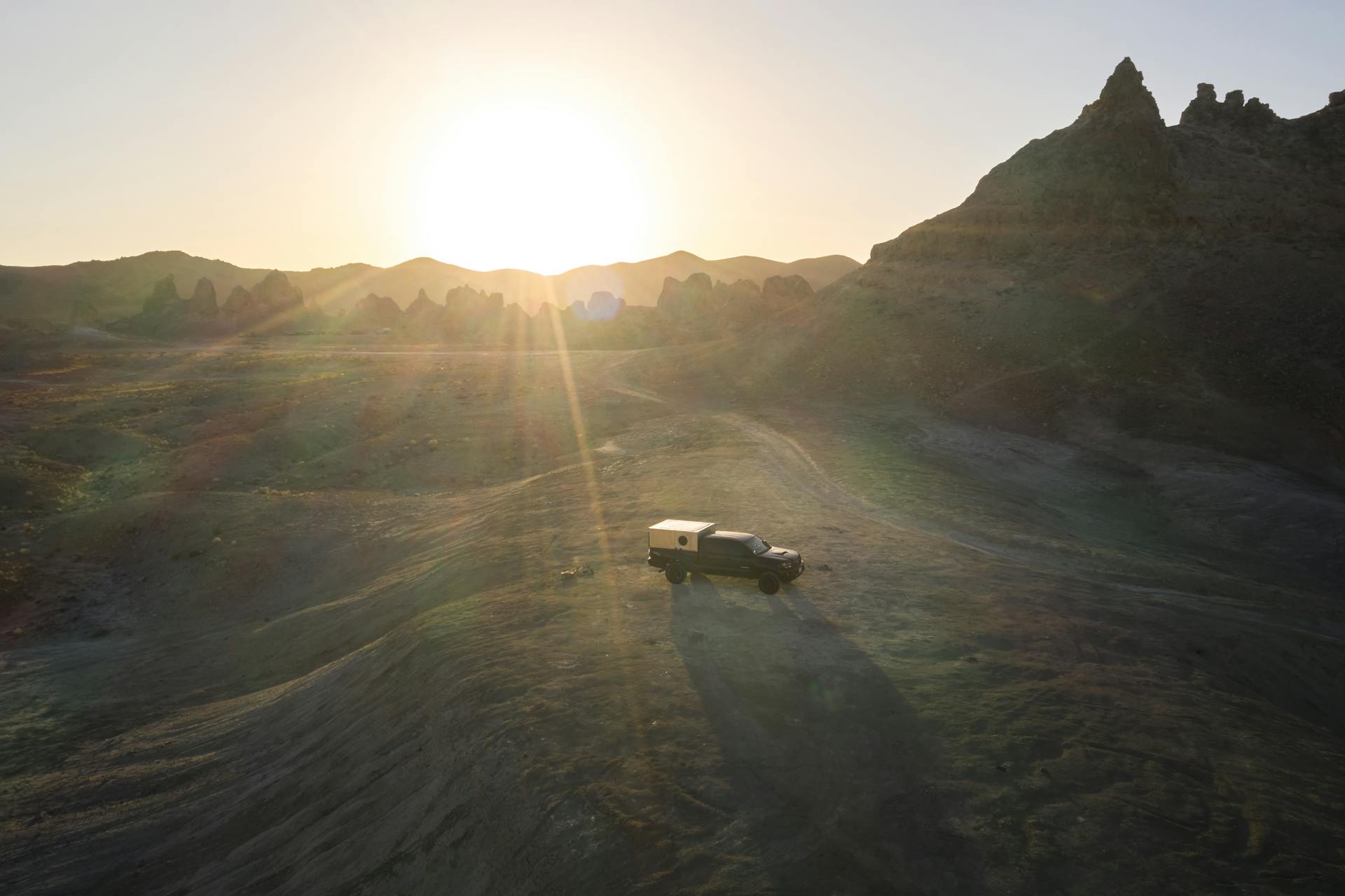 Aerial shot of a truck in San Bernardino County desert with a stunning sunset background.