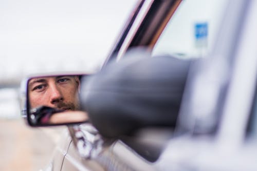 Male driver in car looking in side mirror