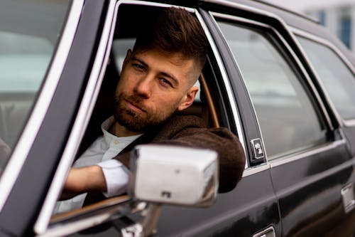 Confident man with trendy hairstyle on vintage car