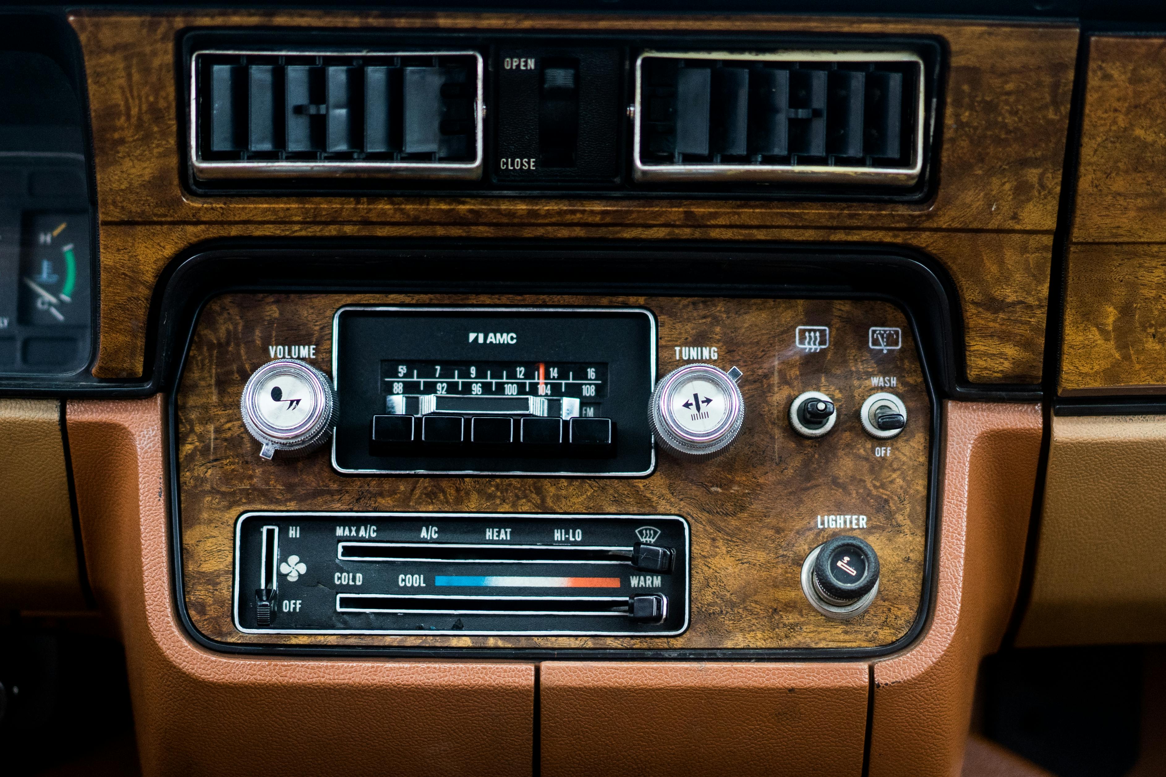 Close-up of a vintage car dashboard featuring a classic radio and control system with wood paneling.