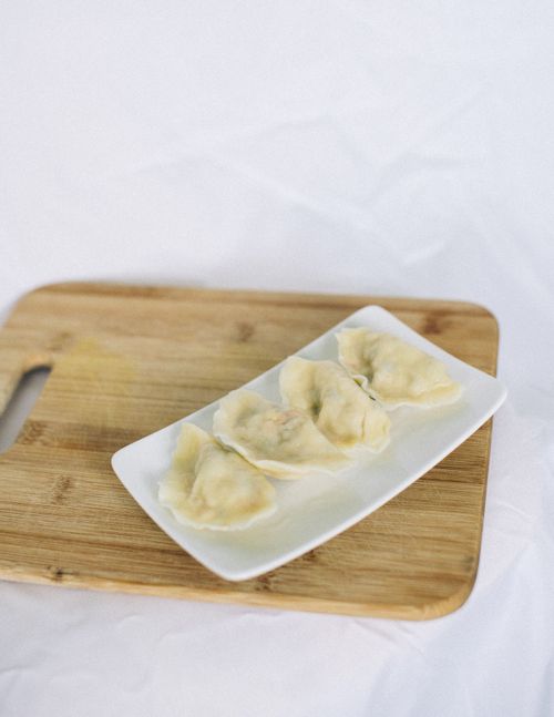 Free A plate of homemade dumplings on a wooden board, ideal for food blogs. Stock Photo