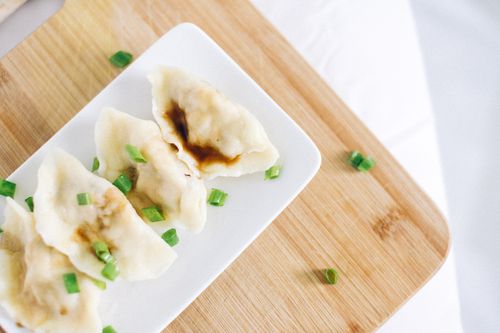 Free Delicious steamed dumplings served on a ceramic plate with onion leaves garnish. Stock Photo