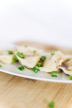 A close-up view of tasty Chinese dumplings garnished with green onions on a plate.