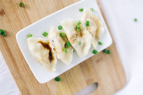 Free Close-up of Chinese dumplings garnished with green onions on a wooden cutting board. Stock Photo